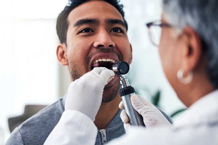 A dentist performing oral cancer screening during a routine dental checkup in St. Louis, MO.