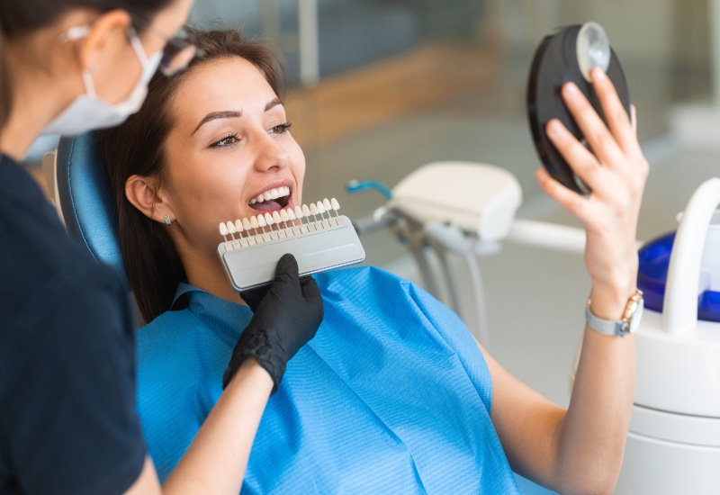 A dentist matches porcelain veneer shades for a patient during a consultation in St. Louis, MO